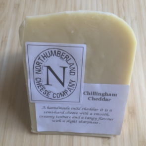A bar of Northumberland Cheese Company Chillingham Cheddar cheese, wrapped in natural paper and placed on a light wood surface against a pale yellow background.